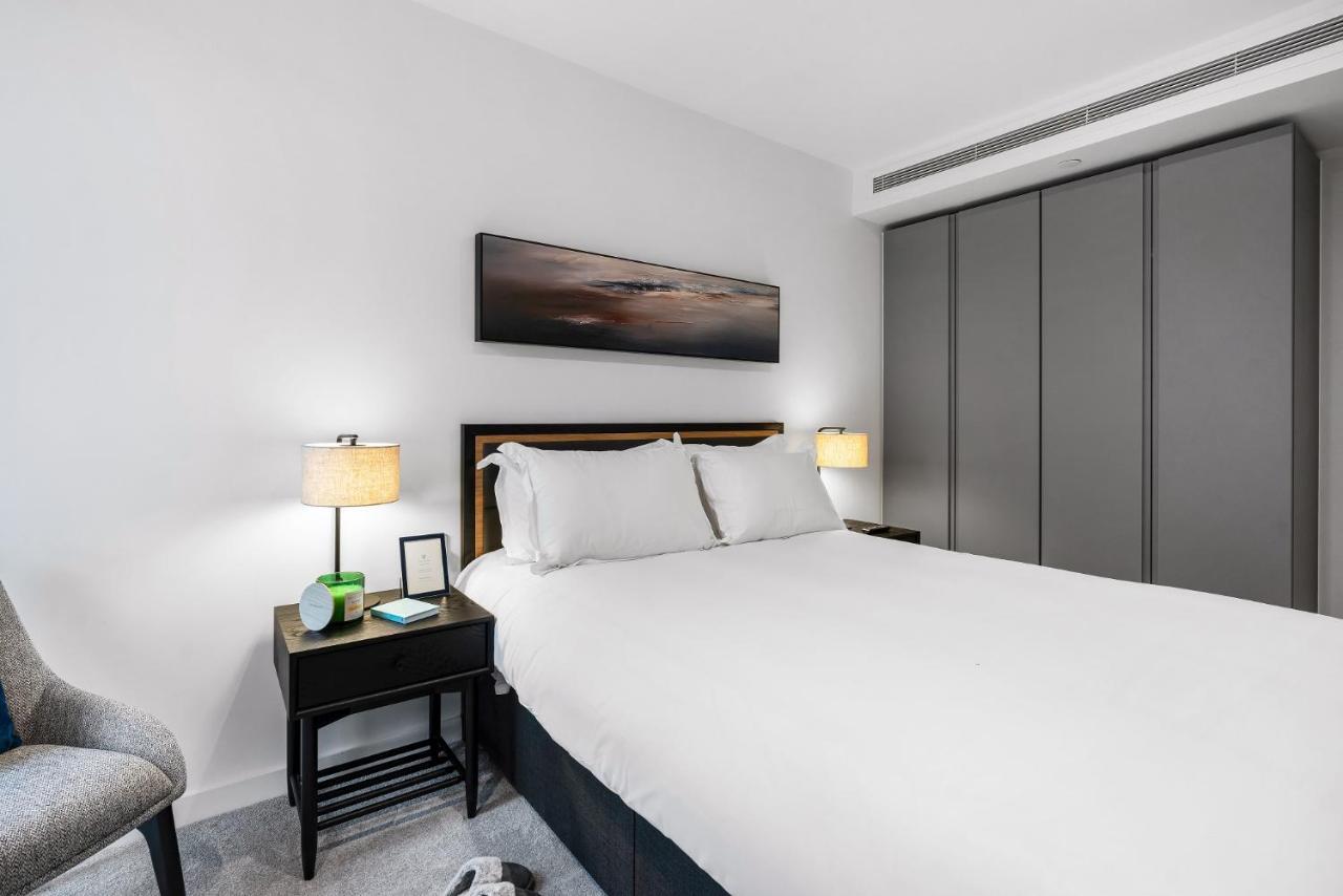 Citysuites 2 Aparthotel マンチェスター エクステリア 写真 The photo shows a modern bedroom with a neatly made bed featuring white linens and pillows. Flanking the bed are two bedside tables, each with a lamp providing soft lighting. There is a piece of artwork above the bed, which appears to depict a landsc