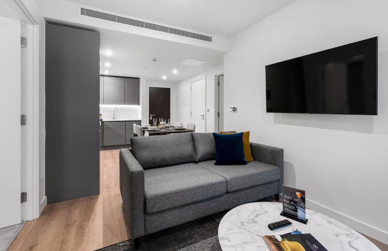 Citysuites 2 Aparthotel マンチェスター エクステリア 写真 The photo shows a modern living space that includes a gray sofa with colorful cushions, a round marble coffee table, and a flat-screen TV mounted on the wall. In the background, there is a kitchen area featuring sleek cabinets. The flooring is light 