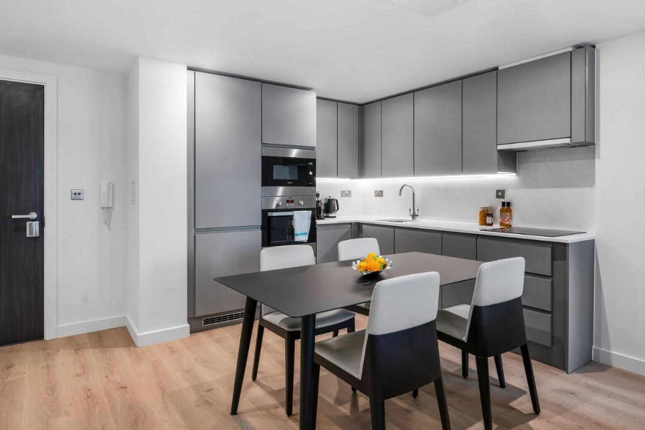 Citysuites 2 Aparthotel マンチェスター エクステリア 写真 The photo shows a modern kitchen with a sleek and minimalist design. The cabinetry features a gray finish, and there are built-in appliances, including an oven and possibly a microwave. The countertop is light-colored, providing contrast to the darke