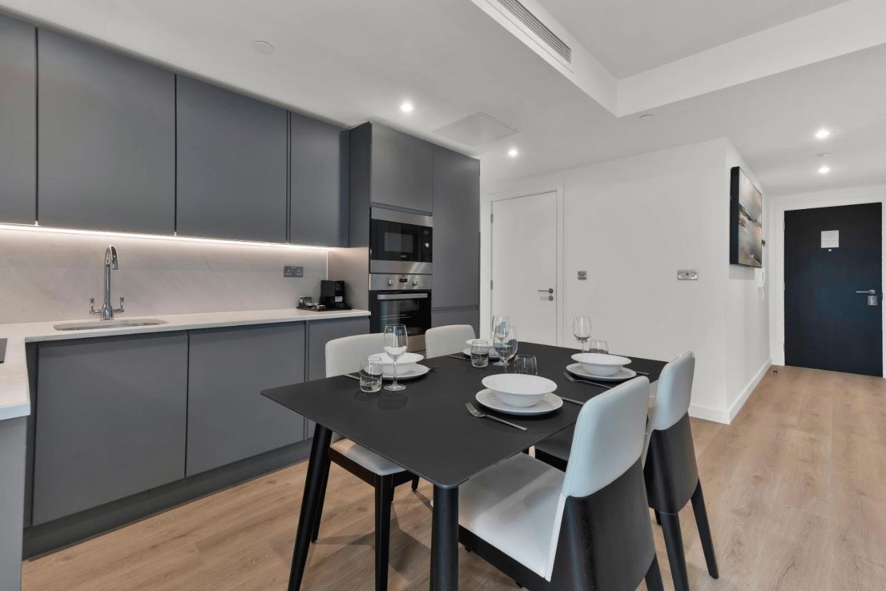 Citysuites 2 Aparthotel マンチェスター エクステリア 写真 The photo shows a modern kitchen and dining area. There are sleek gray cabinetry and countertops, with a built-in oven and microwave. The kitchen is well-lit, featuring under-cabinet lighting that adds to the contemporary feel. In the dining area, th