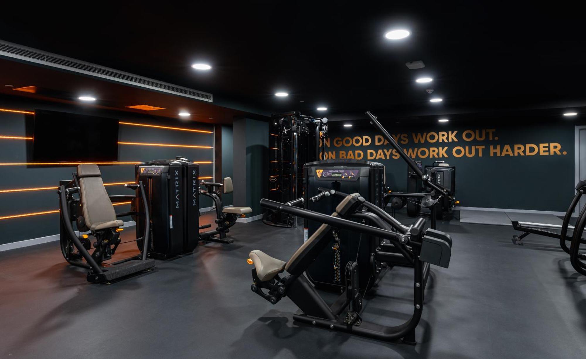 Citysuites 2 Aparthotel マンチェスター エクステリア 写真 The photo shows a modern gym interior. The gym features various exercise machines, including weight training equipment. The flooring is dark, and the walls are adorned with motivational text that reads, "ON GOOD DAYS WORK OUT. ON BAD DAYS WORK OUT HA